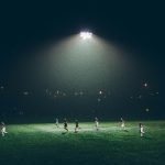 Jugadores en un campo de futbol durante un partido nocturno, imagen ilustrativa