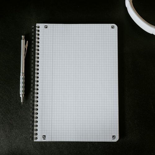 Cuaderno y bolígrafo sobre un escritorio, fotografía ilustrativa del aprendizaje con podcasts
